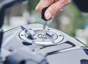 Hand inserting a key into a motorcycle gas cap lock