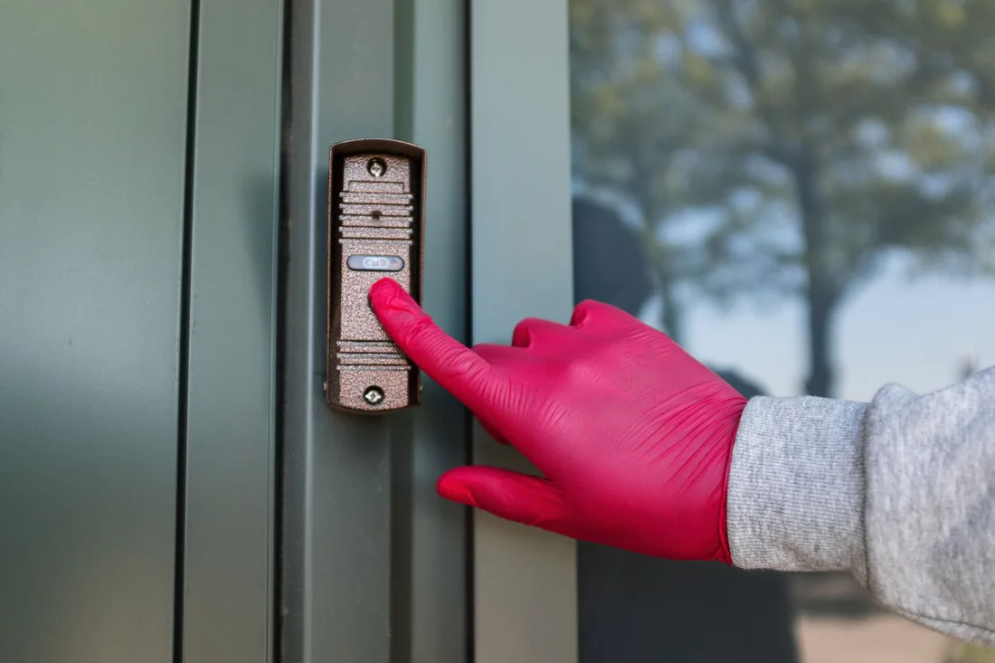 Person pressing the call button on a door entry system
