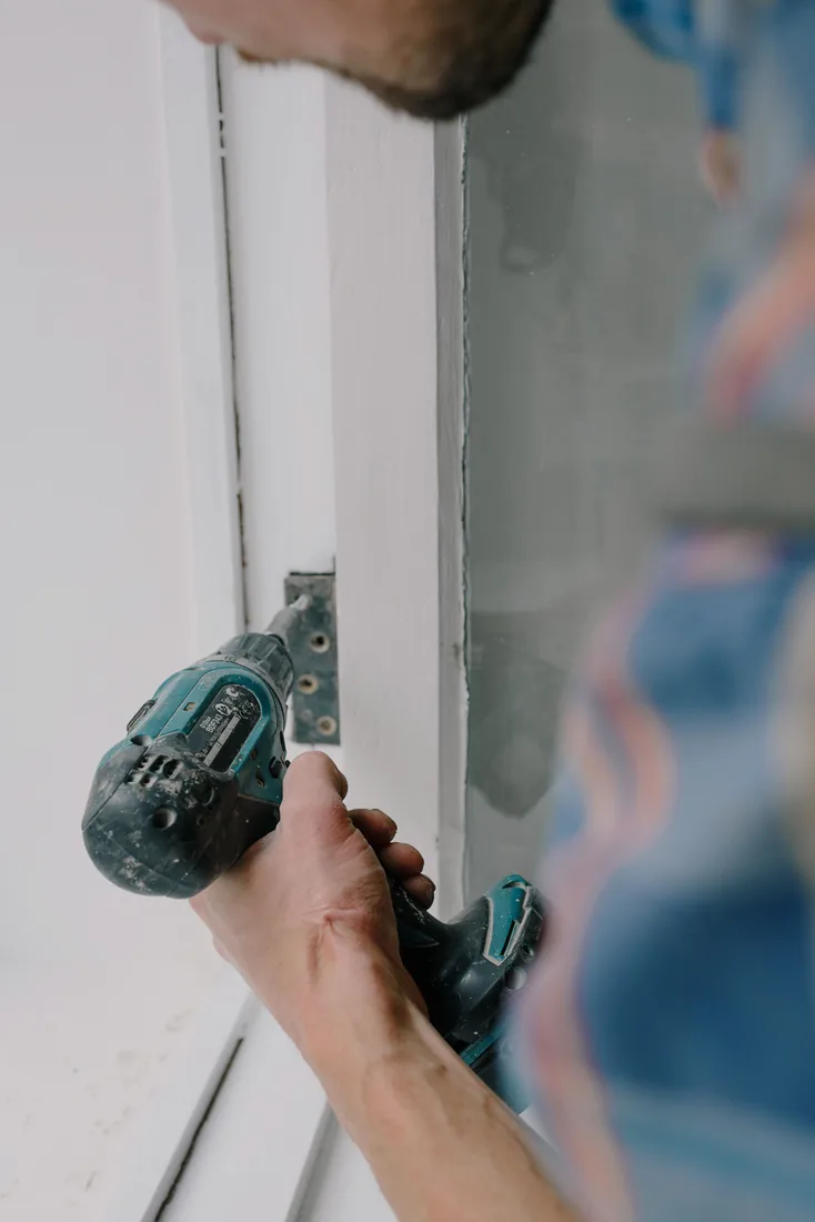 Technician repairing a commercial door with a power drill
