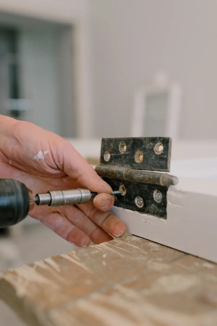 Installer screwing a metal plate onto a door edge
