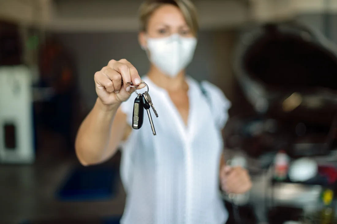 Customer holding a replacement car key at a repair shop