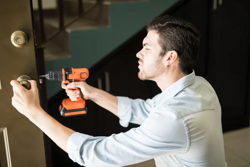 Home Locksmith installing a door knob with a power drill